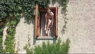 A shameless girl strips and masturbates in an open window
